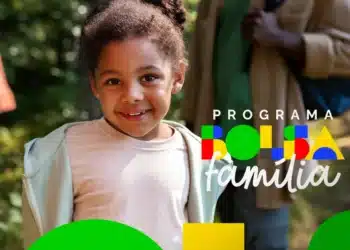 Uma criança sorridente em primeiro plano com o logotipo colorido do Programa Bolsa Família sobreposto à direita. Ao fundo, de forma desfocada, percebe-se a presença de adultos em um ambiente externo iluminado.