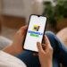 Pessoa segurando celular com a logo do programa Desenrola Brasil aberta na tela