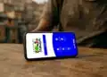 Celular com aplicativo do Bolsa Família aberto sobre mesa