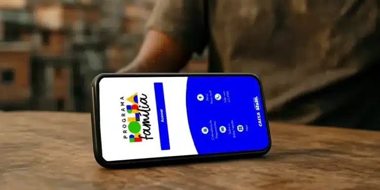 Celular com aplicativo do Bolsa Família aberto sobre mesa