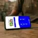 Celular com aplicativo do Bolsa Família aberto sobre mesa