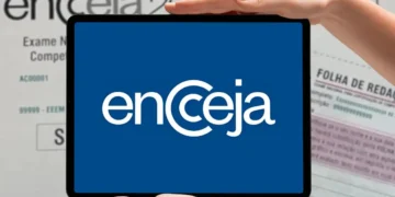Logo do Encceja exibido em um tablet segurado por duas mãos, com documentos de prova e folha de redação ao fundo.