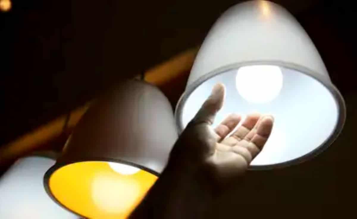 Mão próxima de lâmpadas acesas