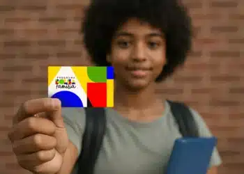 Estudante segurando cartão do Bolsa Família representando regras de frequência escolar do benefício