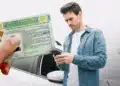 Homem utilizando celular ao lado de um carro enquanto uma CNH aparece em destaque