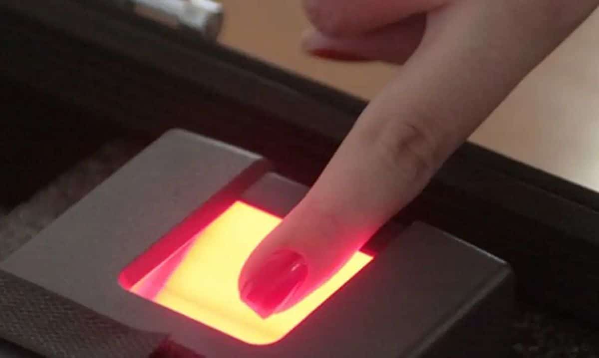 Dedo sendo colocado em leitor biométrico com luz vermelha
