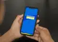 Pessoa segurando celular com aplicativo do Cadastro Único aberto na tela azul