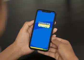 Pessoa segurando celular com aplicativo do Cadastro Único aberto na tela azul