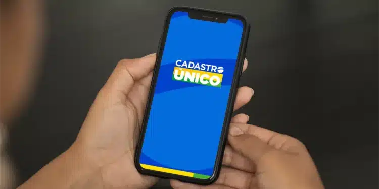 Pessoa segurando celular com aplicativo do Cadastro Único aberto na tela azul