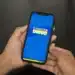 Pessoa segurando celular com aplicativo do Cadastro Único aberto na tela azul