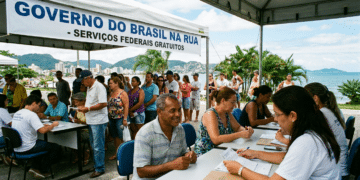 Atendentes recebem cidadãos em mesas sob tenda branca com faixa "Governo do Brasil na Rua" à beira-mar em Floripa