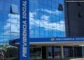 Prédio espelhado azul do INSS com totem e fachada exibindo "Previdência Social" em Brasília