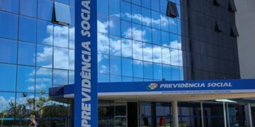 Prédio espelhado azul do INSS com totem e fachada exibindo "Previdência Social" em Brasília