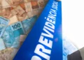 Letreiro azul da Previdência Social ao lado de notas de real de 50 e 100 reais espalhadas ao fundo