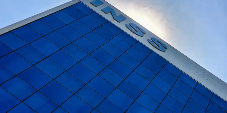Prédio do INSS com fachada de vidro azul refletindo o céu, letras grandes no topo