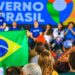 Pessoas assistem a evento do Governo do Brasil, com painel azul, bandeira nacional e participantes no palco