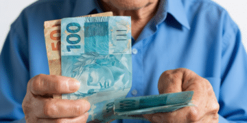 Idoso contando notas de real simboliza aposentadoria em 2026.