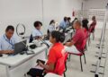 Atendentes do SAC com uniformes azuis atendem cidadãos para emissão da nova CIN em espaço com ring lights e notebooks
