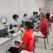 Atendentes do SAC com uniformes azuis atendem cidadãos para emissão da nova CIN em espaço com ring lights e notebooks