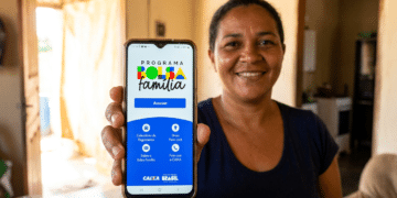 Mulher sorridente mostra tela do aplicativo Bolsa Família com botão Acessar e logotipos da Caixa e Governo Federal