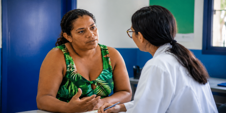 Mulher conversa com profissional em posto de saúde