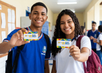 Jovens estudantes sorrindo exibem cartões do Pé-de-Meia em corredor de escola, com uniformes azul e branco