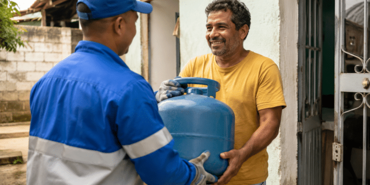 Homem sorridente recebe botijão de gás azul de entregador uniformizado na porta de casa