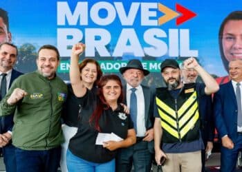 Grupo com autoridades, entregadores sorrindo e braço erguido, fundo Move Brasil azul