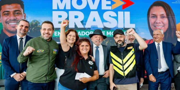 Grupo com autoridades, entregadores sorrindo e braço erguido, fundo Move Brasil azul