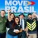 Grupo com autoridades, entregadores sorrindo e braço erguido, fundo Move Brasil azul