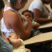 Quatro mulheres amamentam seus bebês sentadas em carteiras escolares, ambiente de sala de aula