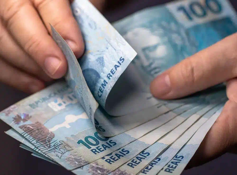 Lucro do FGTS: veja quem tem direito aos valores de R$ 747,33, e R$ 1.121 e quando o dinheiro poderá ser retirado 2 Pessoa segurando notas de reais, representando trabalhadores com direito ao lucro do FGTS em 2026.