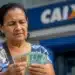 Beneficiária confere dinheiro em frente a uma agência da Caixa, representando os pagamentos do INSS de julho, que começam nesta segunda-feira, 27.