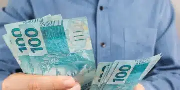 Trabalhador segurando notas de reais, representando os valores do lucro do FGTS em 2026.
