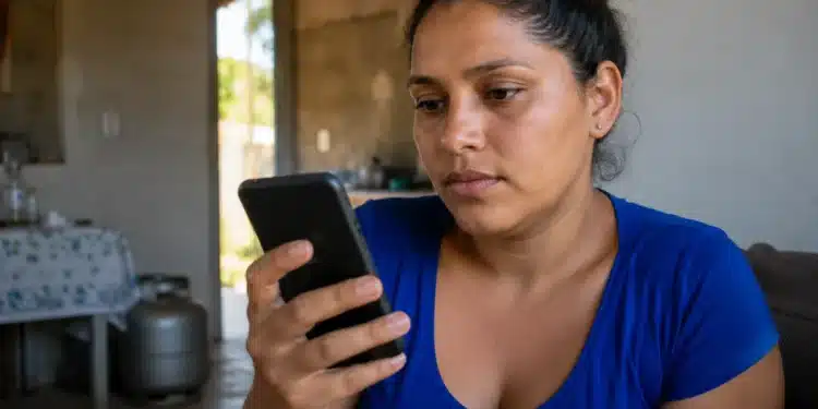 Mulher consulta pelo celular, no app Meu Social, informações sobre o vale-recarga do Gás do Povo.