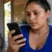 Mulher consulta pelo celular, no app Meu Social, informações sobre o vale-recarga do Gás do Povo.