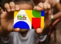 Mãos seguram cartão do Bolsa Família em referência à continuidade dos pagamentos do programa