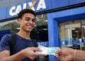 Estudante segurando dinheiro em frente a uma agência da Caixa, representando o pagamento do Pé-de-Meia.
