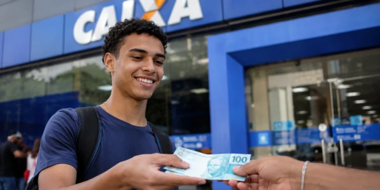 Caixa paga parcela do Pé-de-Meia nesta segunda (24) para 3,6 milhões de estudantes 1 Estudante segurando dinheiro em frente a uma agência da Caixa, representando o pagamento do Pé-de-Meia.