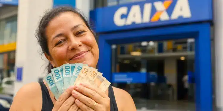 Saque-aniversário do FGTS: nascidos em agosto podem resgatar o valor até 31 de outubro 1 Trabalhadora segura cédulas de real em frente a uma agência da Caixa, representando o saque-aniversário do FGTS para nascidos em agosto.