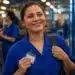 Trabalhadora de uniforme azul segura crachá em fábrica após anúncio de mudanças na jornada de trabalho com fim da escala 6x1.