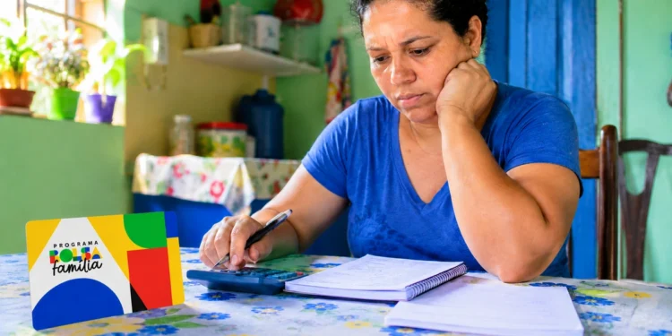 Mulher faz cálculos do orçamento doméstico diante de material do Bolsa Família, representando a manutenção do benefício em 2027.