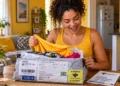 Mulher abre pacote internacional com roupas, representando a isenção da taxa das blusinhas para compras de até US$ 50.