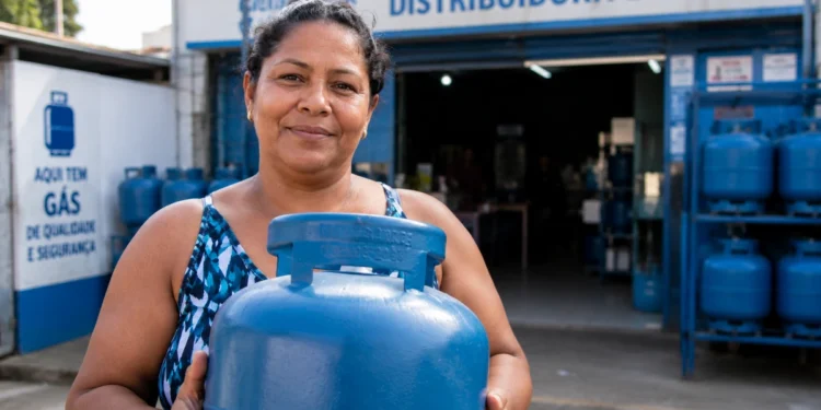 Beneficiária do Gás do Povo segura botijão em frente a uma revenda credenciada.
