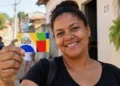 Beneficiária segura cartão do Bolsa Família representando a atualização do valor mínimo do programa em outubro.