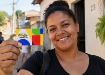 Beneficiária segura cartão do Bolsa Família representando a atualização do valor mínimo do programa em outubro.
