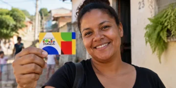 Beneficiária segura cartão do Bolsa Família representando a atualização do valor mínimo do programa em outubro.