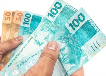 Notas de reais em mãos representando o pagamento dos benefícios do INSS de setembro para segurados