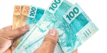 Notas de reais em mãos representando o pagamento dos benefícios do INSS de setembro para segurados