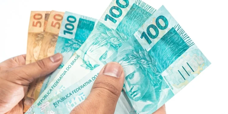 Notas de reais em mãos representando o pagamento dos benefícios do INSS de setembro para segurados